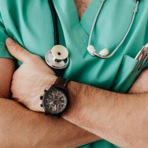 Close-up of a healthcare professional with arms crossed wearing medical scrubs and stethoscope.